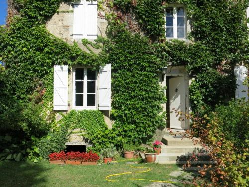 a house covered in ivy with a door and flowers at Au Relais de Nèche. in Bègues