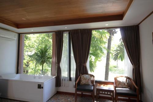 a bathroom with a tub and two chairs and a large window at Royal Train Garden Resort in Chiang Mai