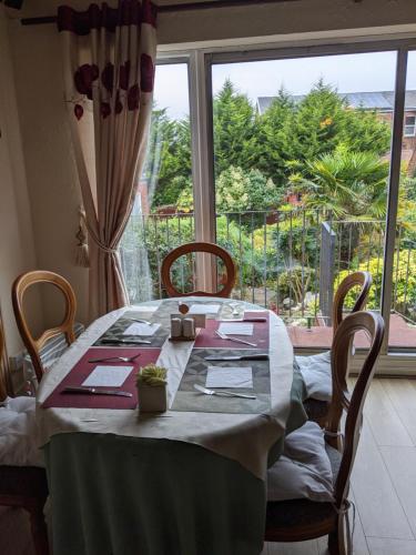 a dining room table with a view of a window at Balmoral Lodge Hotel in Southport