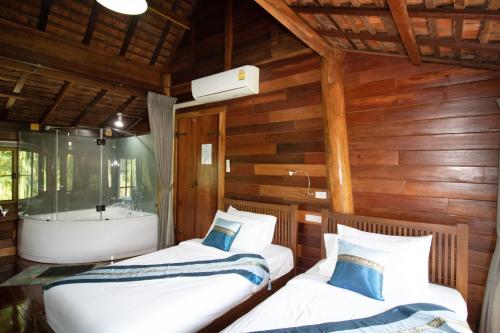 two beds in a room with a bath tub at Royal Train Garden Resort in Chiang Mai