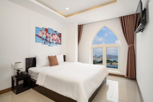 a white bedroom with a bed and a window at Phuong Dong Hotel and Apartment in Quy Nhon