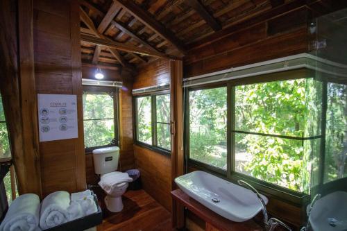 a bathroom with a toilet and a sink and windows at Royal Train Garden Resort in Chiang Mai