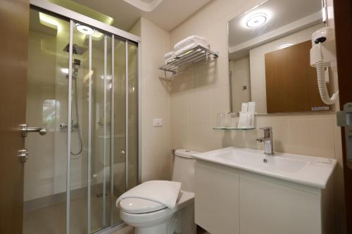 a bathroom with a shower and a toilet and a sink at Justice Hotel in Bangkok
