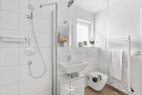 a white bathroom with a shower and a sink at Hakuna Matata in Olpenitz