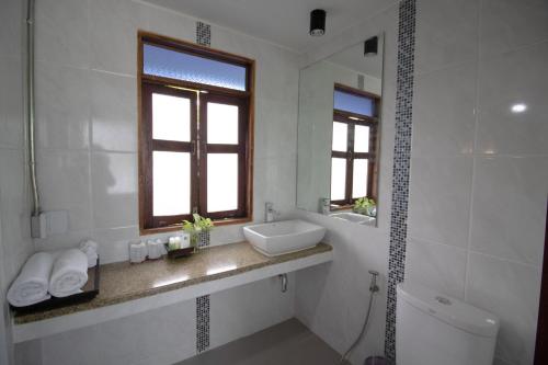 a white bathroom with a sink and a window at Royal Train Garden Resort in Chiang Mai