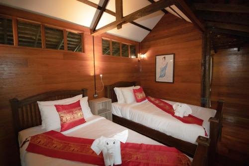 two beds in a room with wooden walls at Royal Train Garden Resort in Chiang Mai