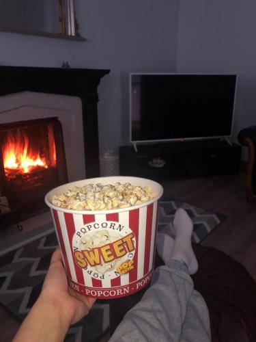 a person holding a cup of popcorn in a living room with a fireplace at Littles Cottage, heart of the Mournes in Annalong