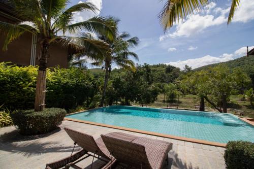 a swimming pool with two chairs and palm trees at Royal Train Garden Resort in Chiang Mai
