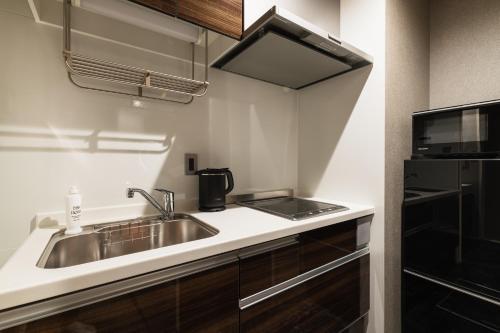 a kitchen with a sink and a microwave at GRAND BASE Hakata Naraya in Fukuoka