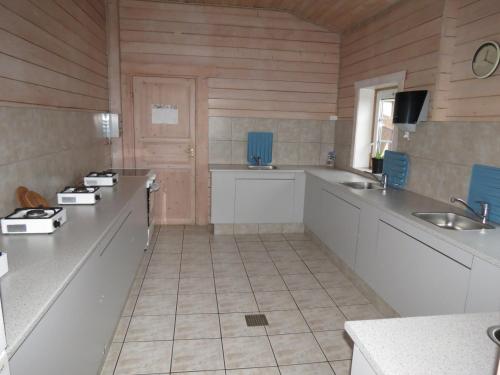 een keuken met witte werkbladen en een houten muur bij Holme Å Camping & Cottages in Hovborg