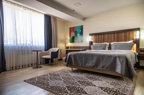 a bedroom with a bed and a desk and a window at Avenue Park Hotel in Yusufkhona