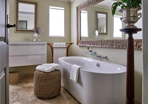 a bathroom with a large tub and a mirror at Deux Frères Wine Estate & Luxury Villas in Stellenbosch