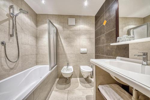 a bathroom with a tub and a toilet and a sink at Hotel Ratschingserhof in Racines