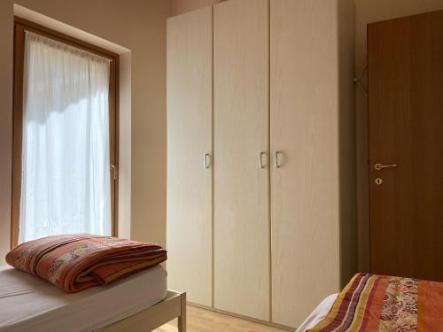 a bedroom with white cabinets and a bed and a window at Residence Valentino in Pinzolo