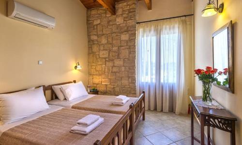 a bedroom with two beds and a stone wall at Exclusive Crete Villa Villa Myrrini 3 Bedroom Private Pool Rethymnon in Astérion