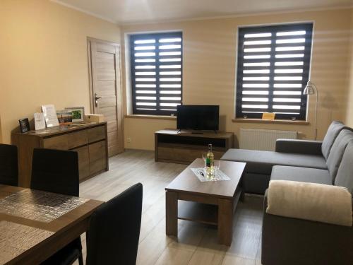 a living room with a couch and tables and windows at Apartamenty ALICJA in Dzierżoniów