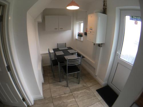 cocina con mesa y sillas en una habitación en 5 bedrooms, 2 Reception Rooms, 2 Shower Rooms, Sleeps up to 7, Parking, Free WiFi & Netflix, Large Garden en Corby