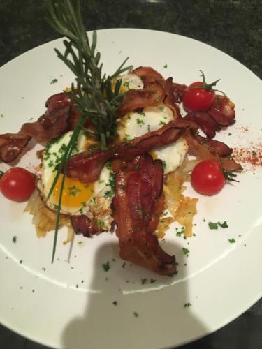 a plate of food with bacon and eggs and tomatoes at Hotel Schützenhaus in Uznach