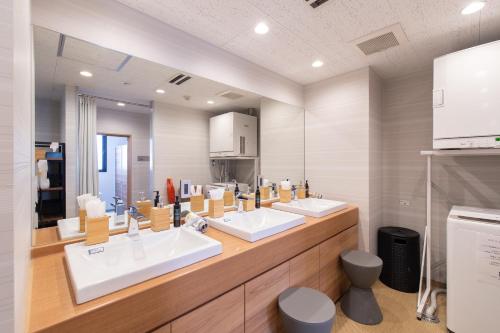 a bathroom with three sinks and a large mirror at Tabist Hotel Smart Sleeps Oita Station in Oita