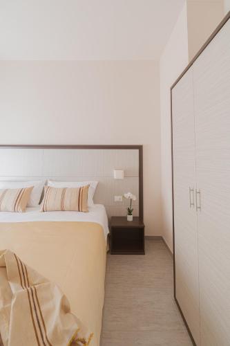 a white bedroom with a large bed and a cabinet at La Maison Di Carla in Ancona