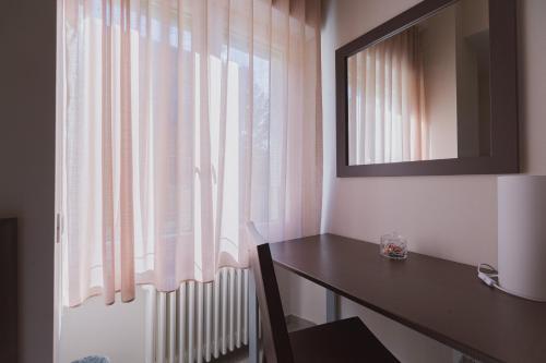 a room with a desk and a window with pink curtains at La Maison Di Carla in Ancona