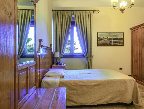 a bedroom with a bed and two windows at Relais Il Mulino in Corigliano Calabro