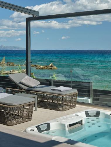 a hot tub on a deck with the ocean at Blue View Villa - Coastal Elegance with Swim Spa, by ZanteWize in Alikanas