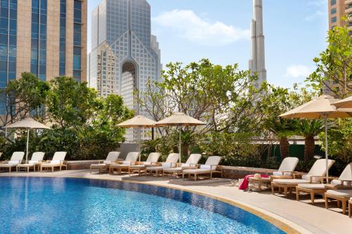 a pool with chaise lounge chairs and umbrellas at Shangri-La Apartments in Dubai
