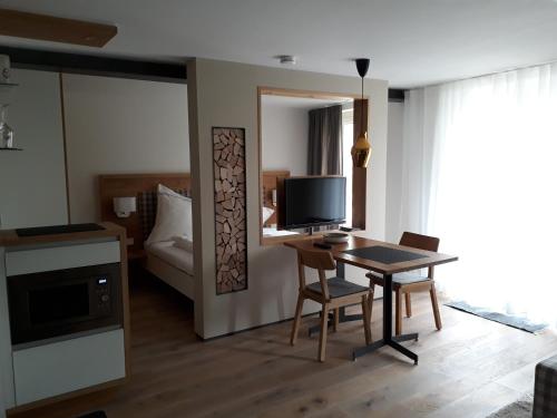 ein Wohnzimmer mit einem Tisch und einem TV sowie ein Schlafzimmer in der Unterkunft Apartment am Kniebach in Immenstaad am Bodensee