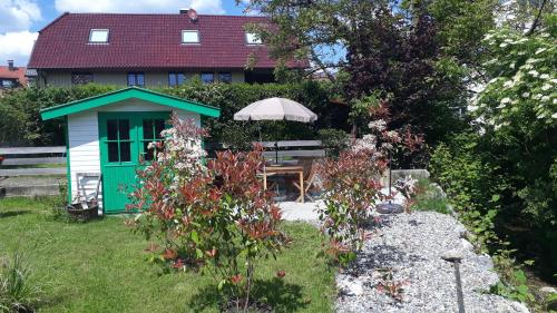 einen Garten mit einer grünen Tür, einem Tisch und einem Sonnenschirm in der Unterkunft Apartment am Kniebach in Immenstaad am Bodensee