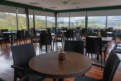 a dining room with tables and chairs and windows at Soraluze Hotela in Oñate