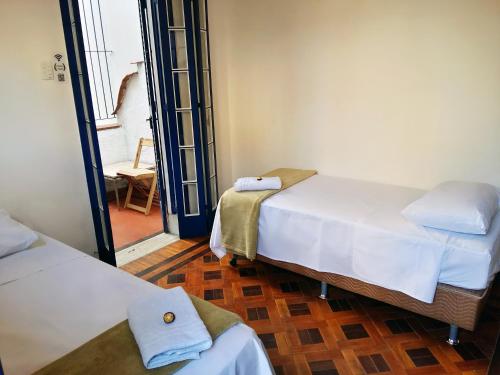 Habitación con 2 camas y pasillo con silla. en Farfalla Guest House, en Río de Janeiro