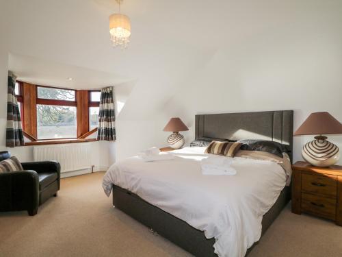 1 dormitorio con 1 cama grande y 1 silla en Orrinside, en Muir of Ord