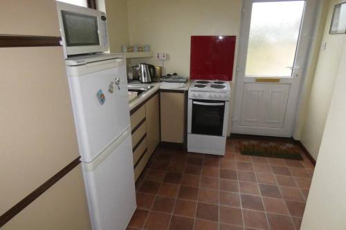 a kitchen with a white refrigerator and a microwave at Ferney Croft in Saint Erth