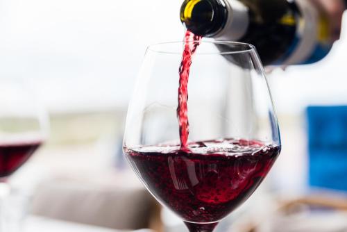 a person pouring red wine into a wine glass at Prominent Inn Hotel in Noordwijk aan Zee
