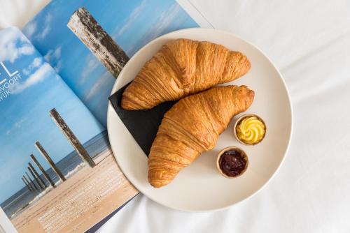 a plate with two croissants and a dipping sauce at Prominent Inn Hotel in Noordwijk aan Zee