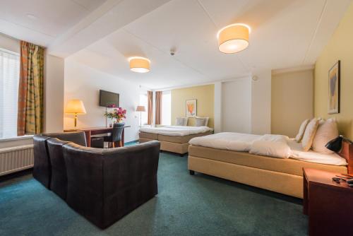 a hotel room with two beds and a couch at Prominent Inn Hotel in Noordwijk aan Zee