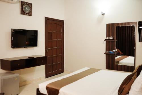 a bedroom with a bed and a tv and a mirror at Diamond Lodge in Karachi