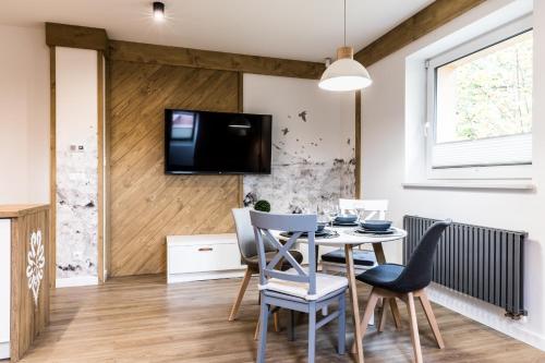 comedor con mesa y sillas y TV en la pared en Apartament przy Bystrej Centrum Odkryj Zakopane en Zakopane