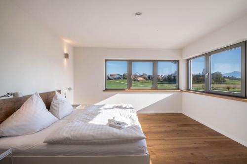 a white bedroom with a bed and windows at Design Ferienhaus 195qm in Breitbrunn am Chiemsee