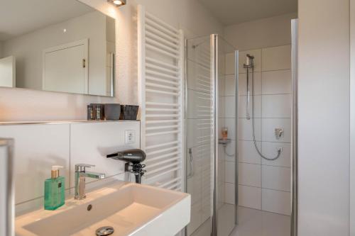 a white bathroom with a sink and a shower at Design Ferienhaus 195qm in Breitbrunn am Chiemsee