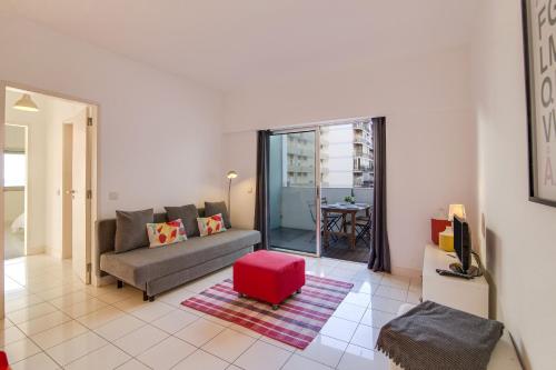 un soggiorno con divano e sgabello rosso di Modern Apartment by the Sea a Quarteira