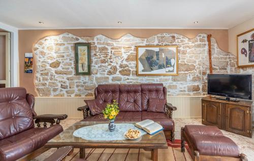 uma sala de estar com mobiliário de couro e uma parede de pedra em House Peresiji em Peresiji