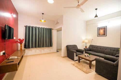 a living room with two couches and a tv at High Q Suites in Bangalore