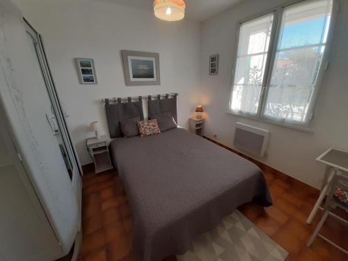 une chambre avec un lit et deux fenêtres dans l'établissement Maison St Martin de Ré, à Saint-Martin-de-Ré