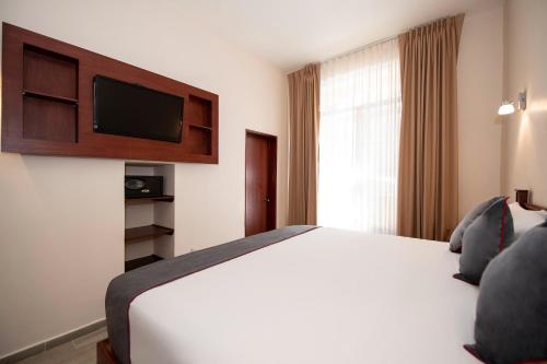 a hotel room with a bed and a television at Hotel Senorial in Querétaro