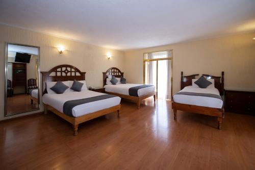 a hotel room with two beds and a mirror at Hotel Senorial in Querétaro