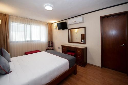 a hotel room with a bed and a mirror at Hotel Senorial in Querétaro
