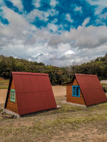 two small buildings with red roofs in a field at Recanto do Vale in Pomerode