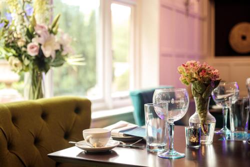 a table with wine glasses and flowers on it at Rowhill Grange Hotel & Utopia Spa in Dartford
